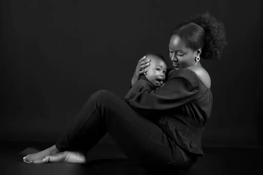 Black and white studio portrait of a mother holding her baby